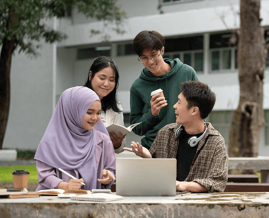 Diverse group of college students discussing project details using laptop at campus park