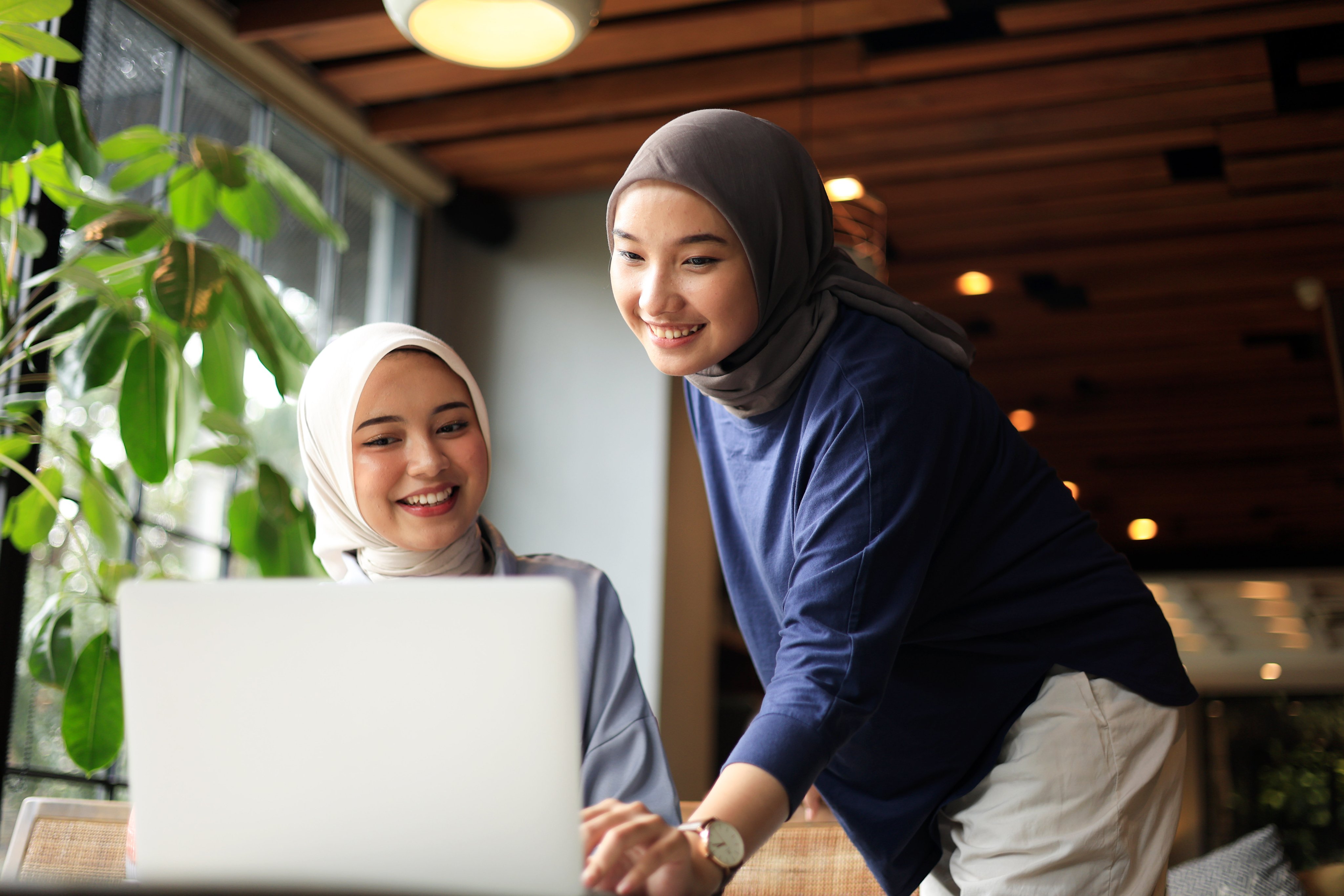 Two Muslim friends wearing hijab working on laptop - Politeknik Digital Indonesia